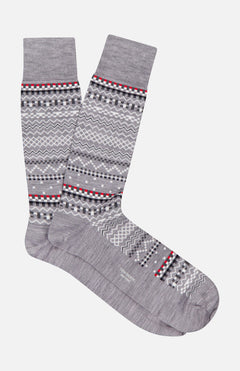 THOM BROWNE Merino Wool Fairisle Jacquard Mid Calf Socks in gray, featuring a geometric pattern with black, white, red, and light gray zigzags and dots. Displayed side by side on a white background. Made in the USA.