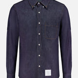The THOM BROWNE Denim Long Sleeve Button Down Straight Fit Shirt features classic Americana style, a chest pocket, white buttons, and a small rectangular white label near the bottom hem.