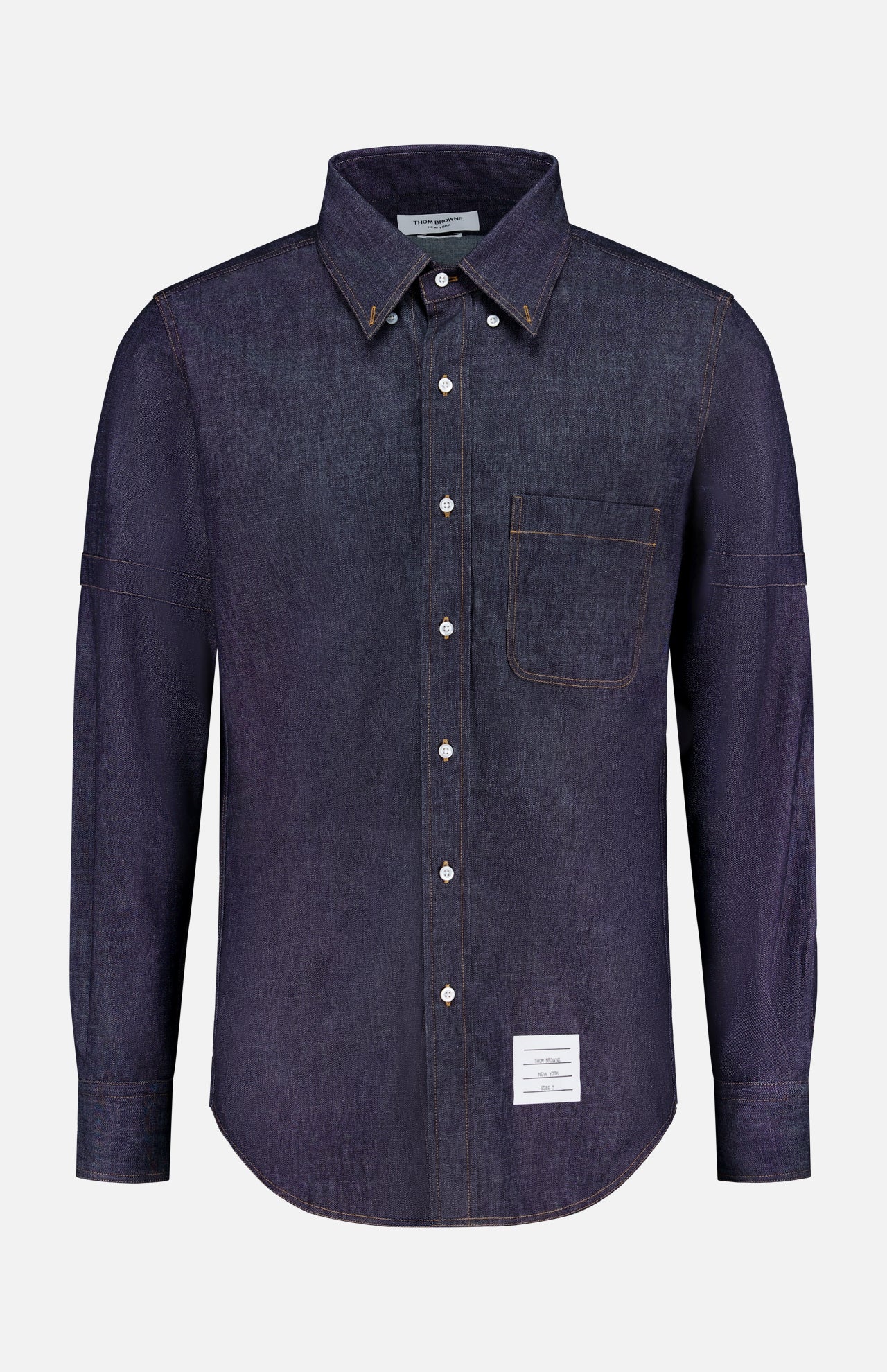 The THOM BROWNE Denim Long Sleeve Button Down Straight Fit Shirt features classic Americana style, a chest pocket, white buttons, and a small rectangular white label near the bottom hem.