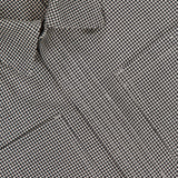 Close-up of the THOM BROWNE Houndstooth Utility Patch Pocket Jacket, featuring a small black and white houndstooth pattern with visible gentle folds and creases in the textured fabric.