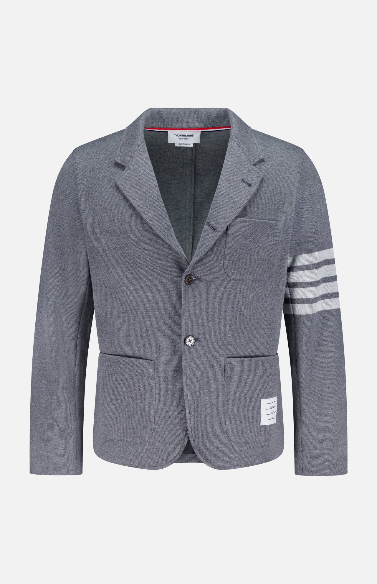 The THOM BROWNE Cotton Knit Sack Jacket is a grey single-breasted sportcoat with two buttons, three white stripes on the left sleeve, three front pockets, and a signature white label above the right pocket hem.