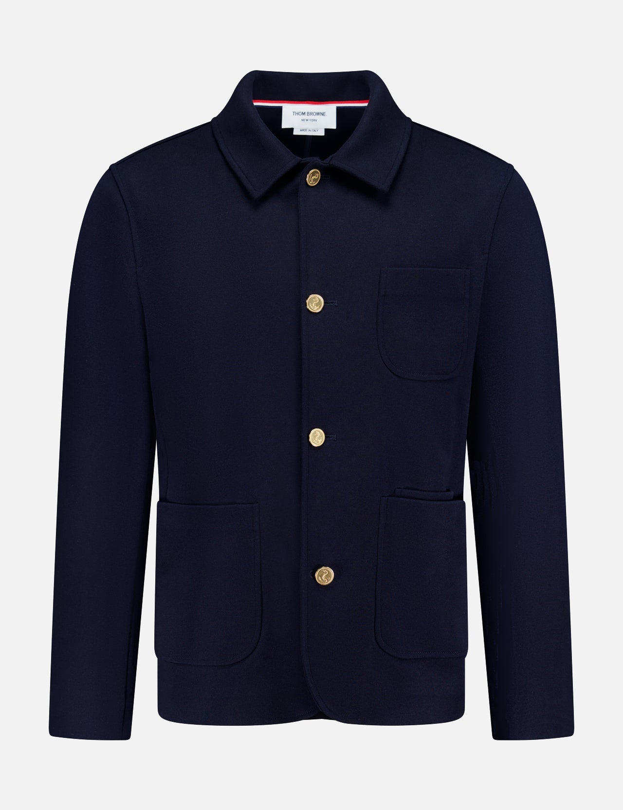 The THOM BROWNE Compact Milano Car Jacket features a collar, long sleeves, gold buttons, and three front pockets in navy, capturing classic Americana style against a plain white background.