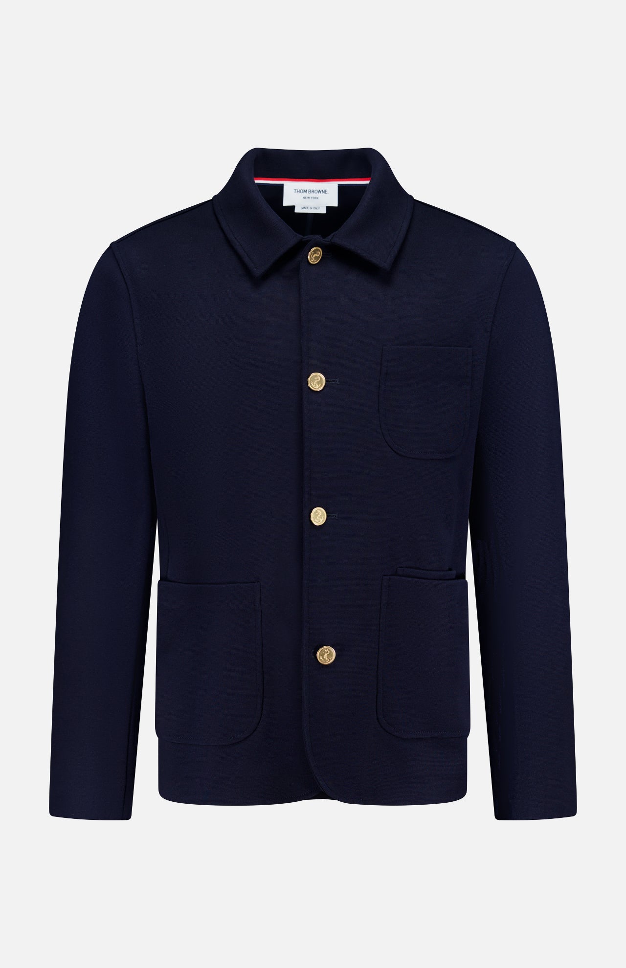 The THOM BROWNE Compact Milano Car Jacket features a collar, long sleeves, gold buttons, and three front pockets in navy, capturing classic Americana style against a plain white background.