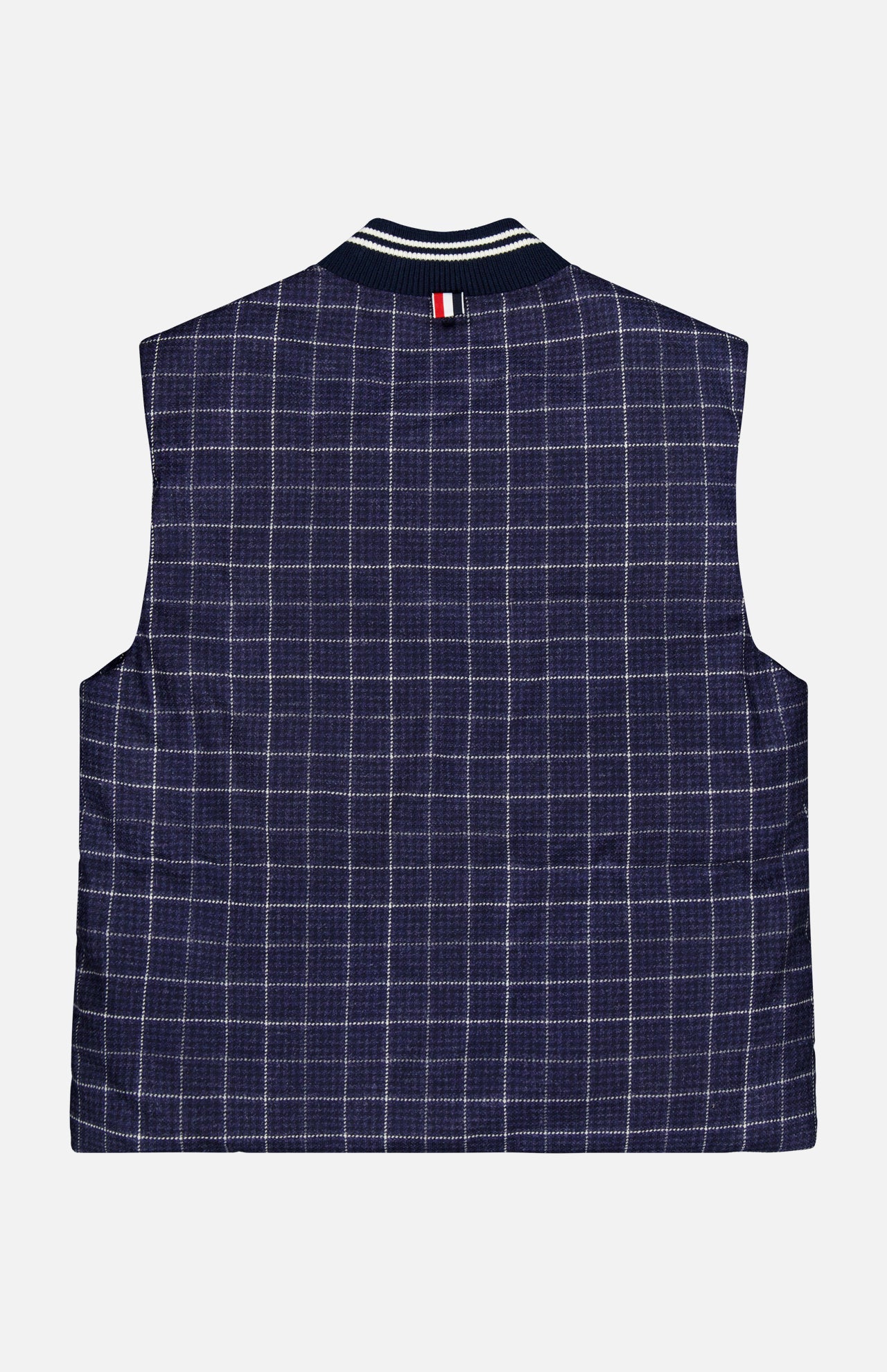 THOM BROWNE’s Houndstooth Teviot Tweed Snap Front Vest is a sleeveless vest featuring a navy blue and white houndstooth pattern, accented with a signature striped tab near the collar. Shown flat with the back facing up against a white background, this piece reflects an American sensibility through its timeless design.