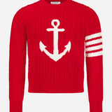 The Intarsia Anchor Merino Wool Crew Neck Sweater by THOM BROWNE is a bold red men’s sweater featuring a large white anchor intarsia on the front and three distinctive white stripes on one sleeve, offering timeless nautical style.