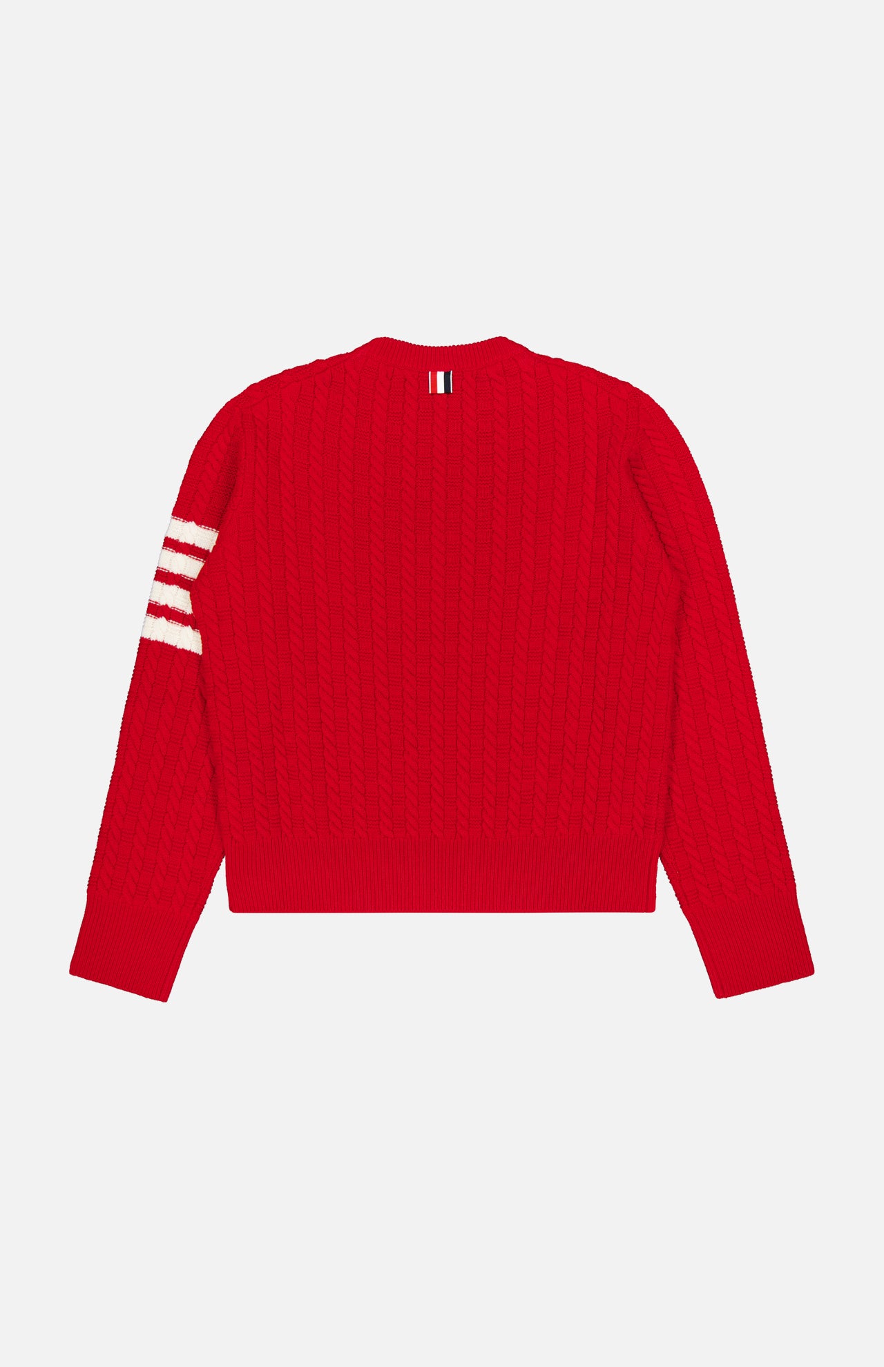 The THOM BROWNE Intarsia Anchor Merino Wool Crew Neck Sweater, a bright red cable-knit men’s sweater with long sleeves, features three white stripes on the left sleeve and a small striped tag at the back neckline. It is displayed laid flat on a white background.