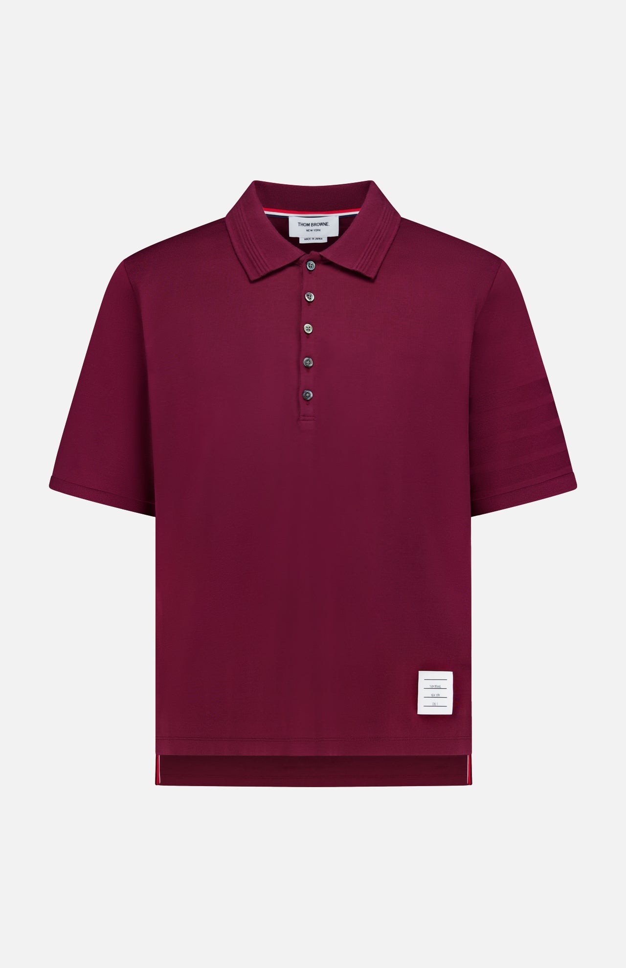 The THOM BROWNE Jersey Short Sleeve Rib Cuff Polo Shirt, a men's classic in burgundy, showcases a smart collar, five-button placket, ribbed cuffs, and a signature small white label near the bottom hem. Presented against a plain white background.