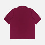 A burgundy THOM BROWNE Jersey Short Sleeve Rib Cuff Polo Shirt is displayed from the back, highlighting its collar and a small striped tag at the neck. This men's polo showcases classic Americana style and is shown laid flat on a white background.