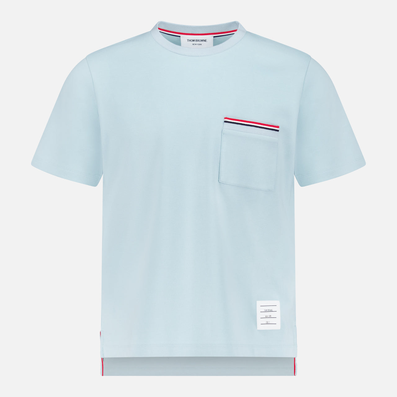 The THOM BROWNE Milano Cotton Pocket Short Sleeve T-shirt is light blue with a front chest pocket trimmed in red, white, and navy, a crew neck, and a small white label near the hem for an Americana casual vibe.