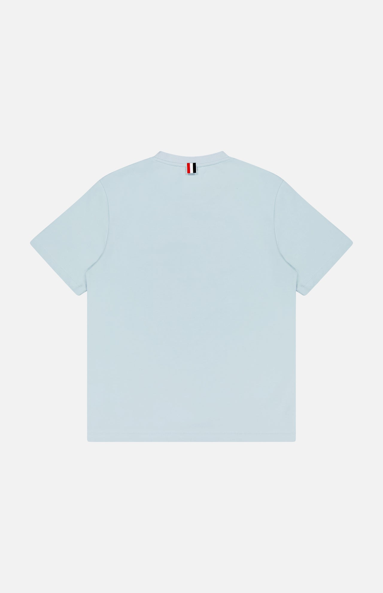 The THOM BROWNE Milano Cotton Pocket Short Sleeve T-shirt is shown from the back in light blue, featuring a small red, white, and black striped tag at the neckline for an Americana-inspired detail.
