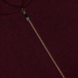 Close-up of a burgundy Milano Stitch Zip Up Bomber Jacket featuring a silver zipper. A white clothing label in the top left corner reads THOM BROWNE. NEW YORK. MADE IN ITALY.
