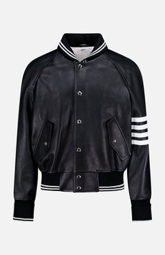 The Oversized Deerskin Leather Bomber Jacket by THOM BROWNE features black leather, white striped ribbed collar, cuffs, hem, left sleeve detail, button closures, and two angled front pockets—an Americana-inspired classic.