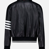 The Oversized Deerskin Leather Bomber Jacket by THOM BROWNE, shown from the back, is black with an oversized varsity style, white stripe on one sleeve, ribbed cuffs and hem, and a small red, white, and blue Americana logo on the collar.