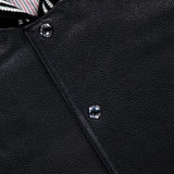 Close-up of the THOM BROWNE Oversized Deerskin Leather Bomber Jacket, with textured black leather, silver snap buttons, and a black-and-white striped ribbed collar for understated Americana style.