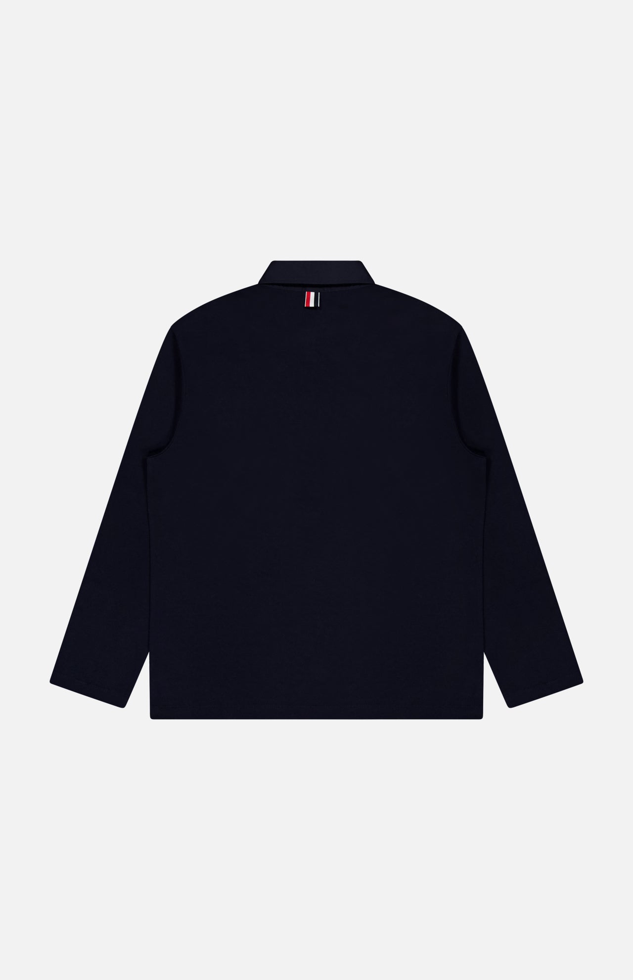 An Oversized Long Sleeve Colorblock Rugby Polo Shirt by THOM BROWNE, shown from the back in dark navy, features a signature small red, white, and blue striped tag below the collar—evoking classic colorblock design elements—set against a plain light gray background.