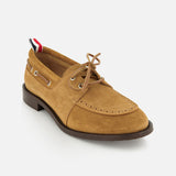 The THOM BROWNE Padded Boat Suede Loafer features tan suede, a brown sole, lace-up front with metal eyelets, and a red, white, and blue striped heel pull tab—combining classic style and elegance, shown on a white background.