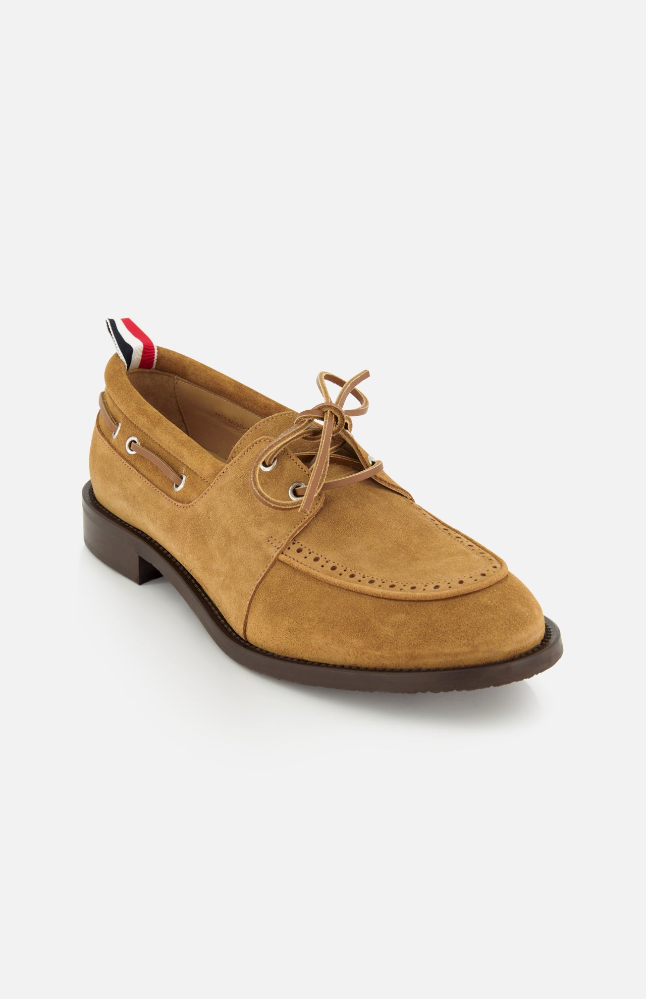 The THOM BROWNE Padded Boat Suede Loafer features tan suede, a brown sole, lace-up front with metal eyelets, and a red, white, and blue striped heel pull tab—combining classic style and elegance, shown on a white background.