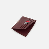 The THOM BROWNE Pebble Grain Leather Card Holder for men, in burgundy leather with multiple card slots and a signature red, white, and black front fabric detail, is shown against a light gray background.