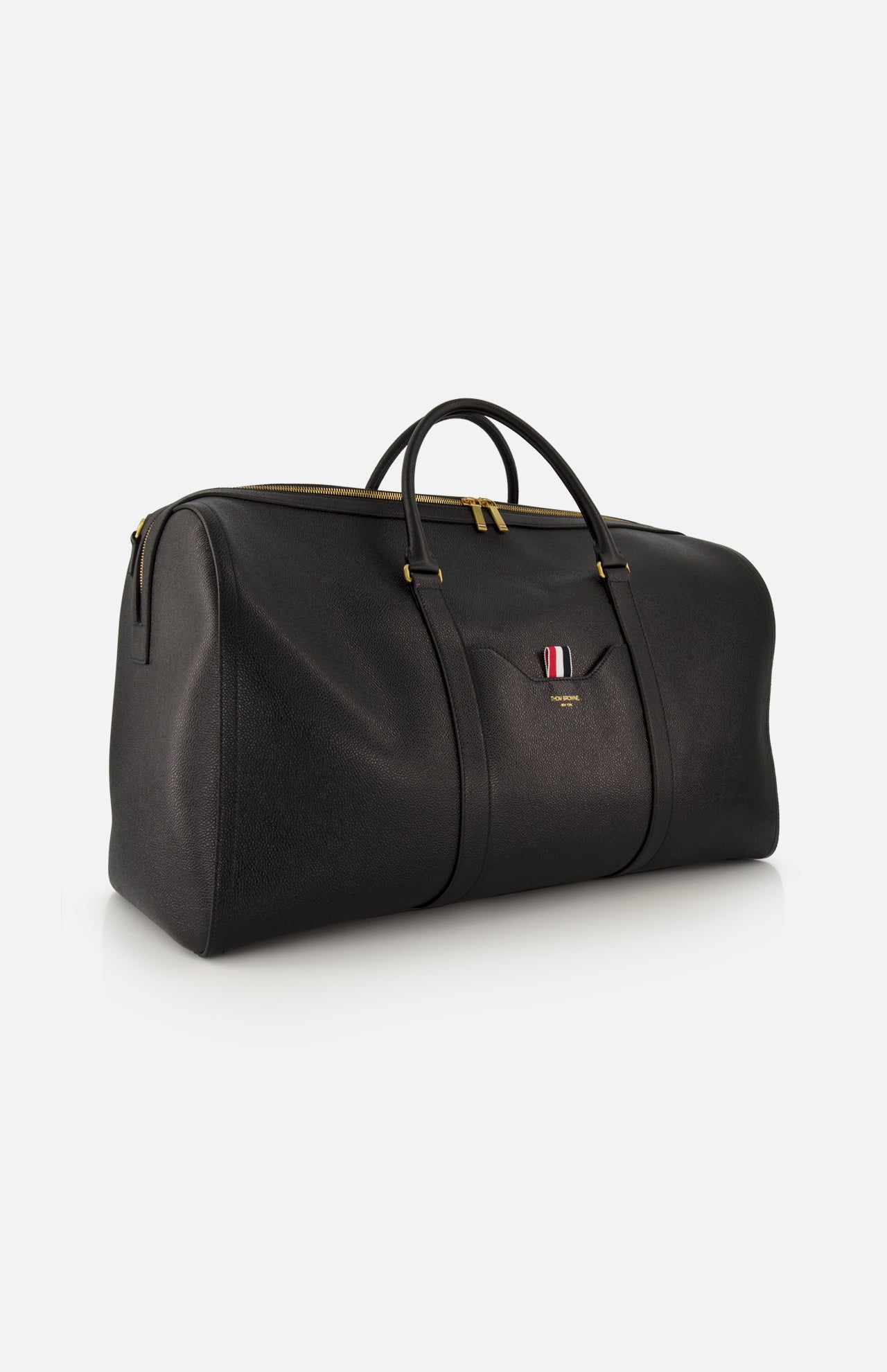 The THOM BROWNE Pebble Grain Leather Duffle Bag is a spacious black travel essential in premium leather with gold zipper, dual handles, and a small pocket accented by the brand's signature red, white, and blue striped detail.