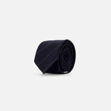 A rolled-up Pinstripe Wool Classic Tie by THOM BROWNE, featuring subtle diagonal stripes in black wool and crafted in Italy, is displayed on a plain light gray background.