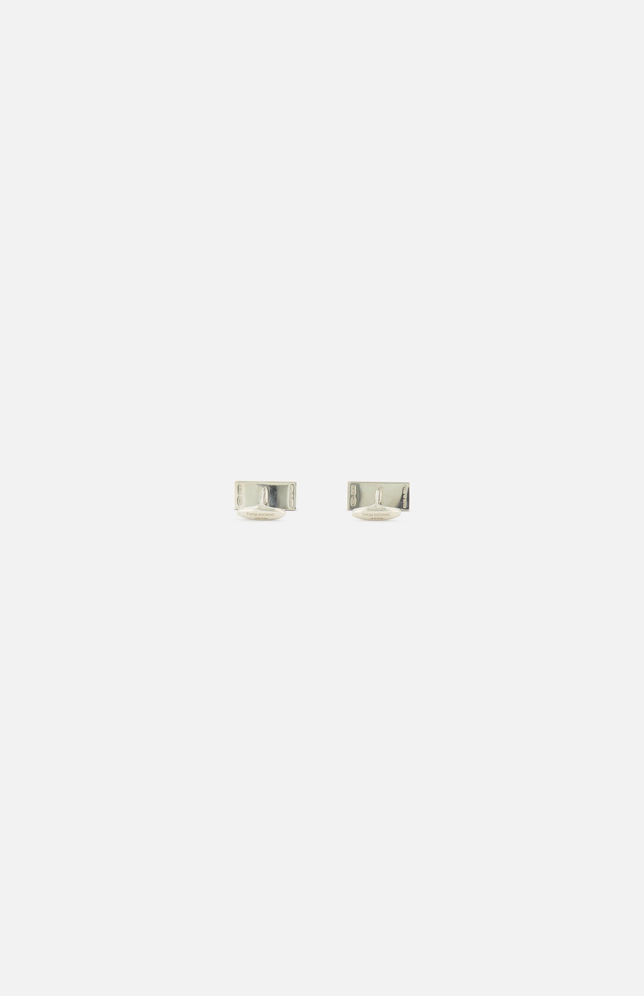 A pair of small, silver RWB Enamel Cufflinks by THOM BROWNE displayed on a plain white background evokes classic Americana style with understated elegance.