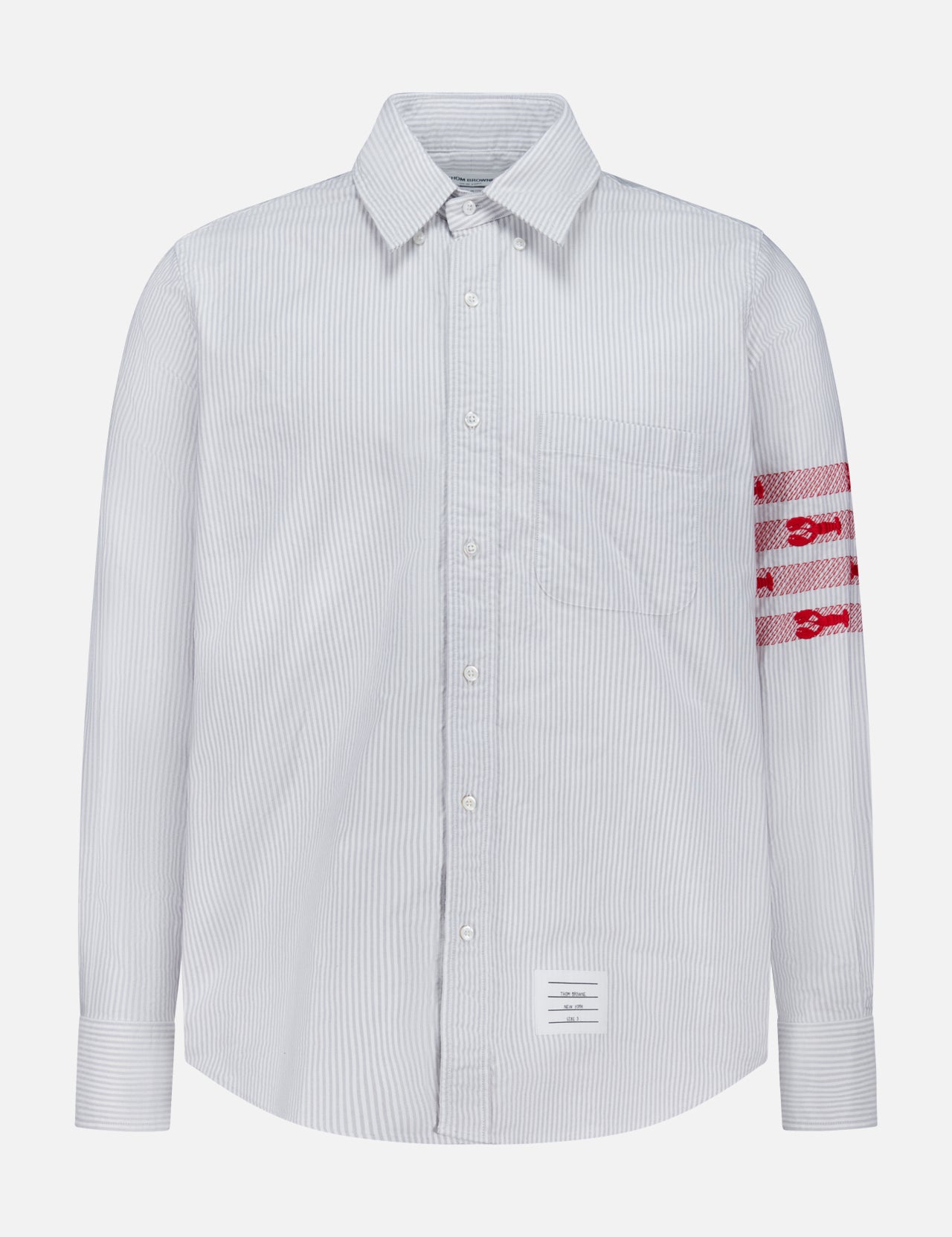 Introducing the Straight Fit Lobsters Long Sleeve Oxford Shirt by THOM BROWNE—a light blue and white pinstriped classic oxford shirt featuring a crisp collar and bold red horizontal bands with white detailing on the left arm. Finished with THOM BROWNE’s signature white rectangular label sewn near the bottom hem, this standout Americana piece is perfect for elevating your coastal summer wardrobe.