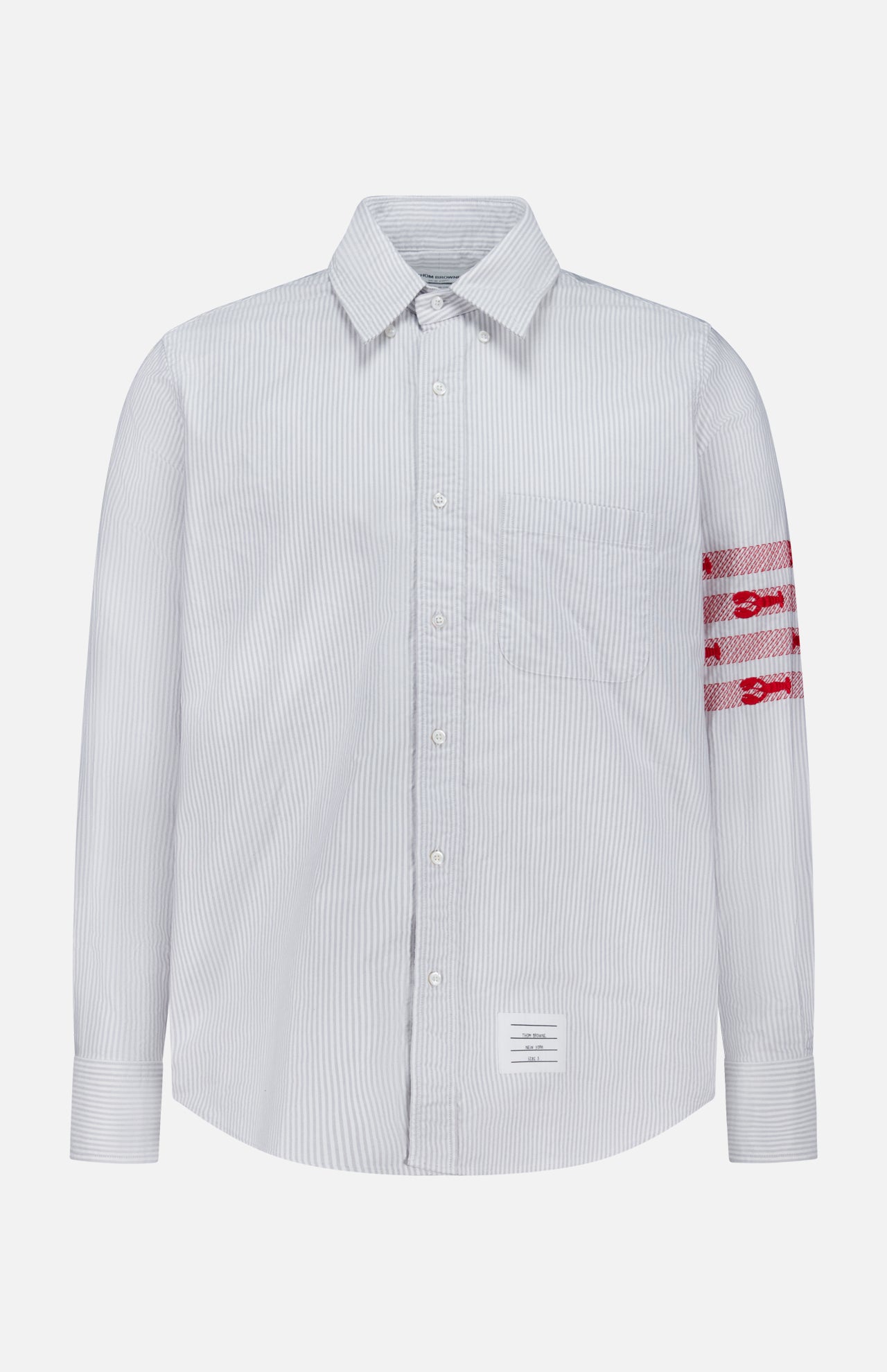 Introducing the Straight Fit Lobsters Long Sleeve Oxford Shirt by THOM BROWNE—a light blue and white pinstriped classic oxford shirt featuring a crisp collar and bold red horizontal bands with white detailing on the left arm. Finished with THOM BROWNE’s signature white rectangular label sewn near the bottom hem, this standout Americana piece is perfect for elevating your coastal summer wardrobe.