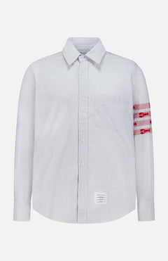 Introducing the Straight Fit Lobsters Long Sleeve Oxford Shirt by THOM BROWNE—a light blue and white pinstriped classic oxford shirt featuring a crisp collar and bold red horizontal bands with white detailing on the left arm. Finished with THOM BROWNE’s signature white rectangular label sewn near the bottom hem, this standout Americana piece is perfect for elevating your coastal summer wardrobe.