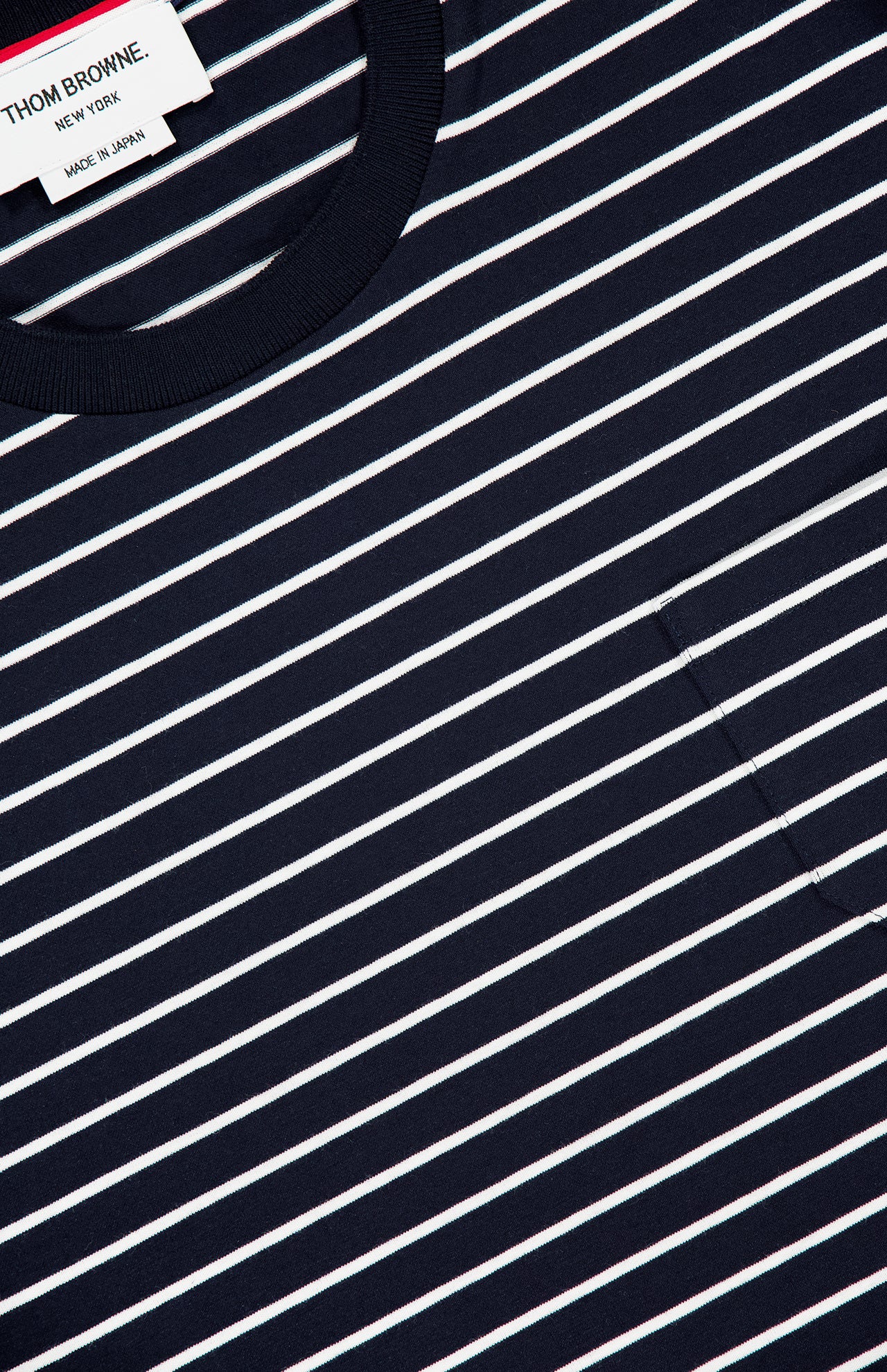 Close-up of the Stripes Jersey Short Sleeve T-shirt by THOM BROWNE, featuring navy and white stripes, round neckline, small chest pocket, and a branded label inside the collar.