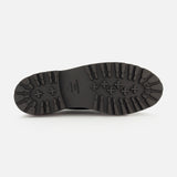 The image shows the underside of a black THOM BROWNE Vitello Calf Leather Derby Loafer sole, featuring thick, rugged tread patterns for traction plus text and sizing information printed in the center.