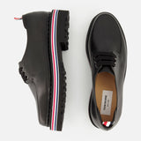 Two THOM BROWNE Vitello Calf Leather Derby Loafers in black are shown on a white background—one side view, one top view. The thick rubber soles display a red, white, and blue stripe along the side.