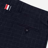 Close-up of THOM BROWNE Windowpane Check Cotton Wool Trouser Pant in navy, featuring a subtle windowpane plaid, single buttoned back pocket, and a belt loop with red, white, and navy stripes.