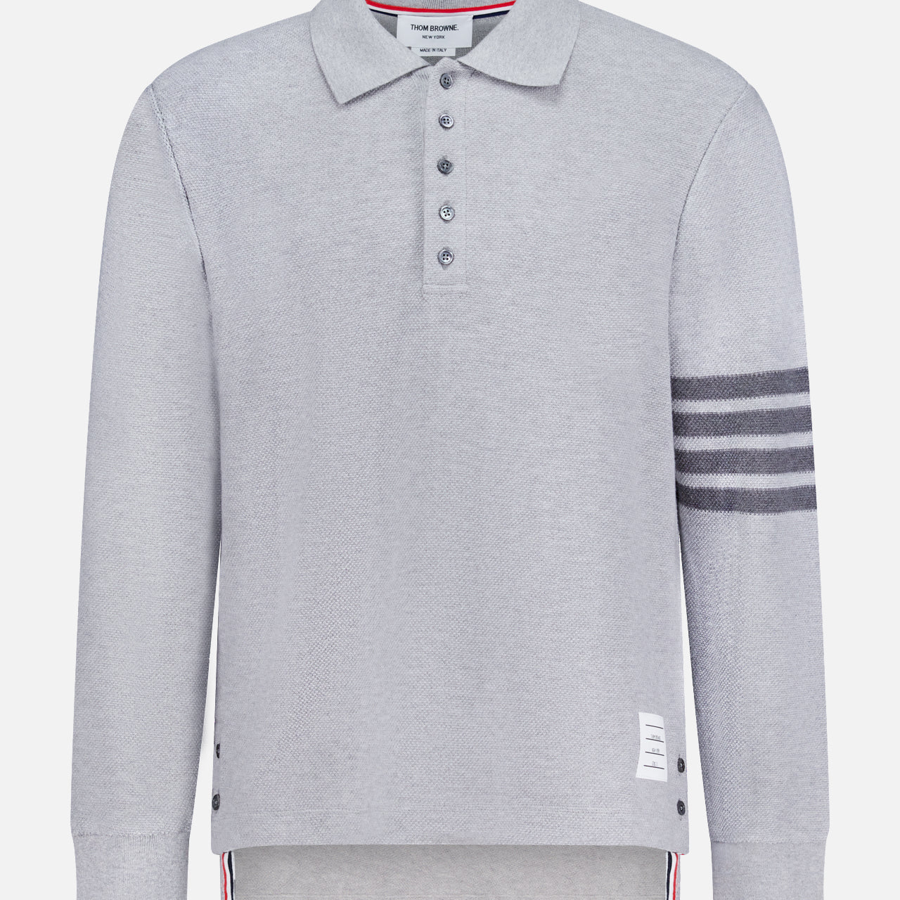 The THOM BROWNE Textured Pique Long Sleeve Polo Shirt features light grey pique cotton, a classic collar, four dark stripes on the left sleeve, side buttons, a buttoned placket, and a signature white label near the hem—a stylish choice for men.