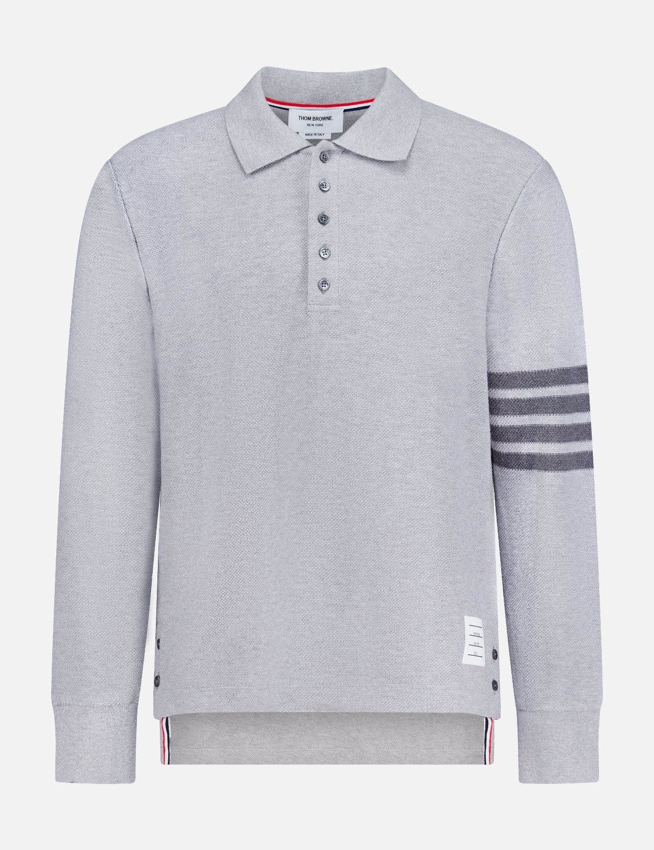 The THOM BROWNE Textured Pique Long Sleeve Polo Shirt features light grey pique cotton, a classic collar, four dark stripes on the left sleeve, side buttons, a buttoned placket, and a signature white label near the hem—a stylish choice for men.