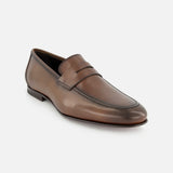 The TO BOOT Aldrin Leather Penny Loafer, a brown men’s shoe with a classic penny strap, visible toe stitching, and a low heel, is shown against a plain white background.