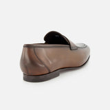 The TO BOOT Aldrin Leather Penny Loafer, shown from a rear side angle, highlights its brown leather finish, low black heel, and classic penny strap—a refined Italian-style shoe set against a light plain background.