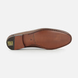 The sole of the Aldrin Leather Penny Loafer by TO BOOT, shown from below, displays smooth brown leather with stitched edges and a small gold and black logo near the heel, reflecting classic Italian loafer style.