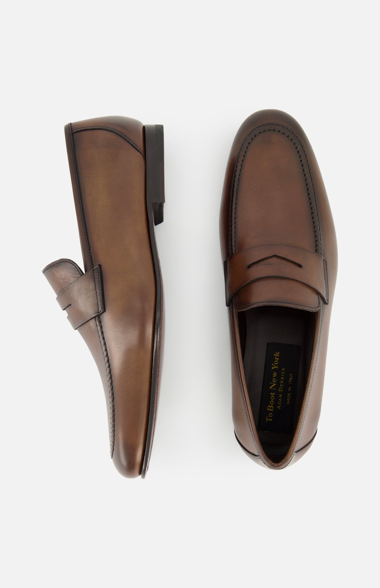 The Aldrin Leather Penny Loafer by TO BOOT is shown in side and top views on a white background, featuring brown polished leather with classic stitching around the toe.