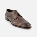 The TO BOOT Blakeley Leather Derby Oxford is a single brown leather lace-up shoe with a closed lacing system, low heel, and slightly pointed toe, made in Italy and shown on a white background.