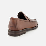 The Fischer Penny Leather Loafer by TO BOOT is pictured from the back, showcasing its rich brown textured leather, low heel, and timeless slip-on design. Crafted in Italy, this loafer features a dark brown sole and is displayed against a plain white background.