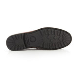 The image displays the bottom view of a black rubber sole featuring textured tread patterns with crosses and lines, engineered for grip and traction, on the TO BOOT Fischer Penny Leather Loafer—a classic slip-on penny loafer crafted from brown leather.