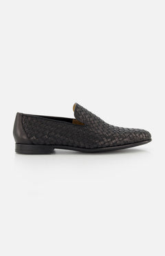 The TO BOOT Foley Woven Loafer, crafted from Italian calfskin in black with a woven pattern, low heel, and slip-on design, is shown in side profile on a white background.