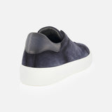 Presenting the James Slip On Sneaker by TO BOOT—a stylish navy blue suede slip-on with a white sole, showcased from the back left angle. The heel is adorned with a dark leather patch featuring embossed lettering, highlighting its expert Italian craftsmanship. This refined sneaker stands out against a plain white background.