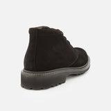 The Javier Suede Chukka Boot by TO BOOT is featured here in black suede, showcased from the back to reveal its thick, textured rubber sole and prominent edge stitching. Set against a plain white background, the refined details of these men’s designer boots stand out.