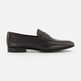The TO BOOT Keats Leather Penny Loafer is shown in a side profile view against a white background—a single black leather loafer with a low heel and sleek, minimalist design, crafted in the classic tradition of Italian leather loafers.