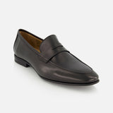 The Keats Leather Penny Loafer by TO BOOT is a sleek, minimalist black Italian leather slip-on with a low heel, showcased on a white background—combining timeless style and modern sophistication for the perfect dress shoe.