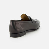 The image displays the TO BOOT Keats Leather Penny Loafer in black, shown from the back against a white background. This slip-on dress shoe features a low heel, a slightly shiny leather finish, and classic penny loafer detailing.