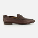 The TO BOOT Merritt Deer Leather Penny Loafer is a classic brown penny loafer crafted from luxurious Italian deer leather, featuring a low heel, visible stitching, and a signature penny strap detail. It is displayed on a plain white background.