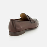 A single Merritt Deer Leather Penny Loafer by TO BOOT, expertly crafted from luxurious Italian deer leather in brown, is displayed from the back and slightly to the side against a plain white background.