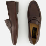 The TO BOOT Merritt Deer Leather Penny Loafer, showcased here in brown Italian deer leather, features one shoe displayed from the side and the other from above against a plain white background. This classic penny loafer design embodies timeless elegance and sophistication.